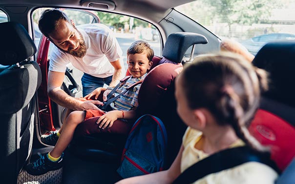 dad buckling son in car seat